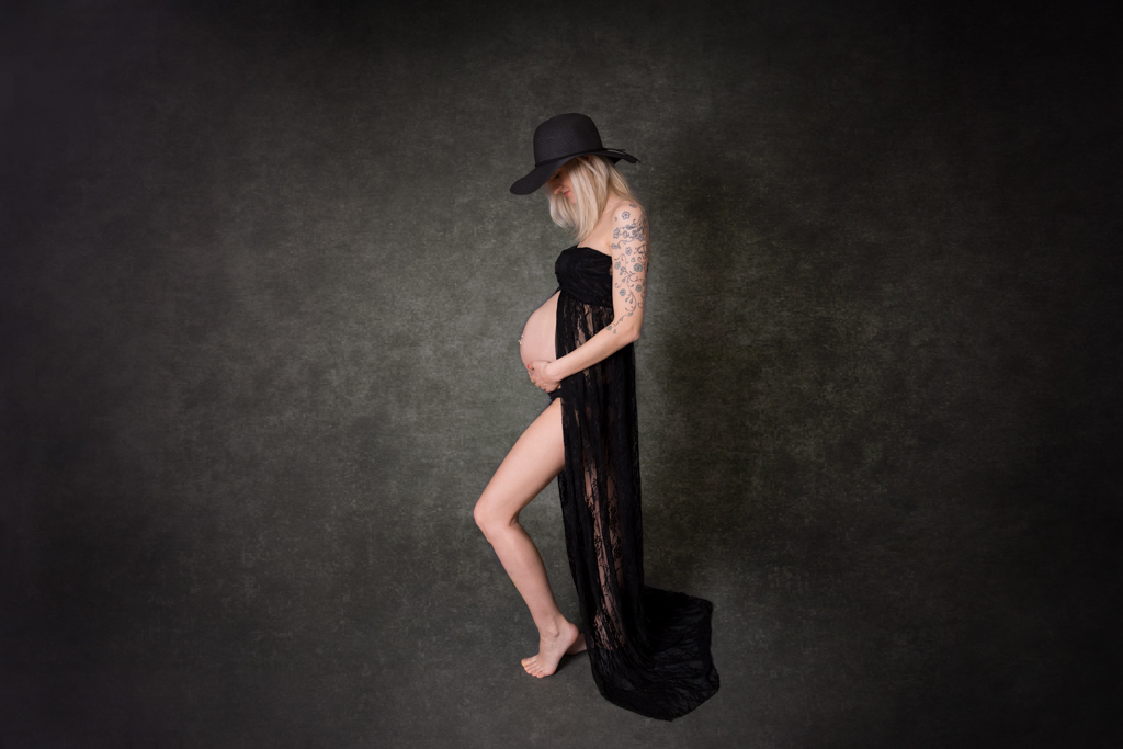 Schwanger im schwarzen Spitzenkleid, das Kleid ist vorne am Bauch offen und man sieht den Babybauch, Studio bei Bergisch Gladbach in Lohmar Bild von Carina Rosen