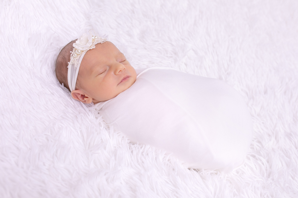 Baby auf weißem Fel, eingepuckt in ein weißes Tuch und schläft, baby tuch foto von carina rosen studio in lohmar