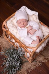 Baby liegt schlafend in einem körbchen und trag weißen overall,Newbornshooting Köln, Babyshooting köln, neugeborenenshooting rösrath