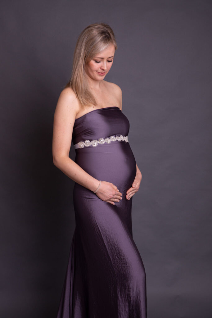 Schwangere in einem lila Tuch vor grauem Hintergrund . in der nähe von Overath von Fotografie Carina Rosen in lohmar