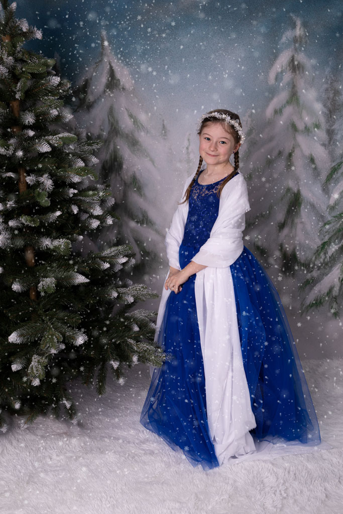 Kleine Eiskönigin im blauen Kleid im Schnee