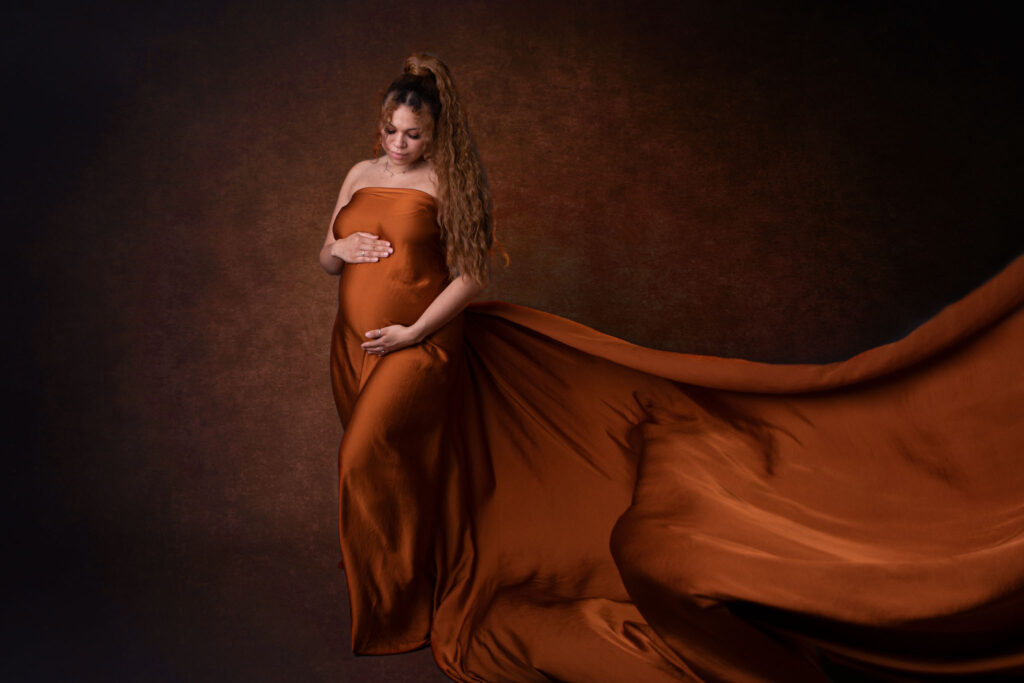 Baldmama trägt ein cognacfarbenes tuch, sie streichelt liebevoll ihren Babybauch, Carina Rosen, schwangerschaftsfotografie lohmar
