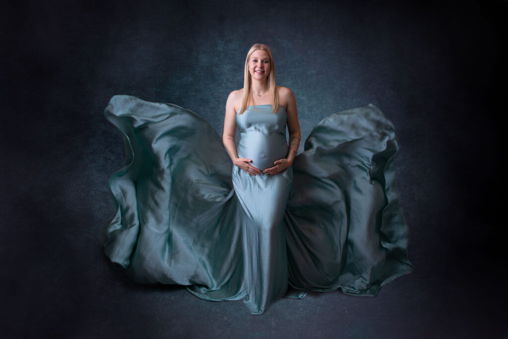 Schwangere in einem blauen Tuch vor dunkelblauen Hintergrund in der nähe von Overath von Fotografie Carina Rosen