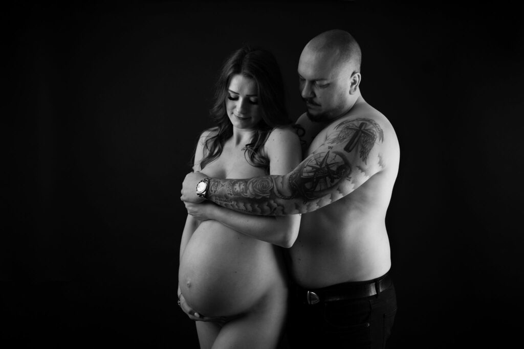 Akt Schwangerschaft mit Partner, der Mann verdeckt ihre Brust und die Schwangere hat ihre Hand auf dem Babybauch, Studio in der Nähe von Rösrath