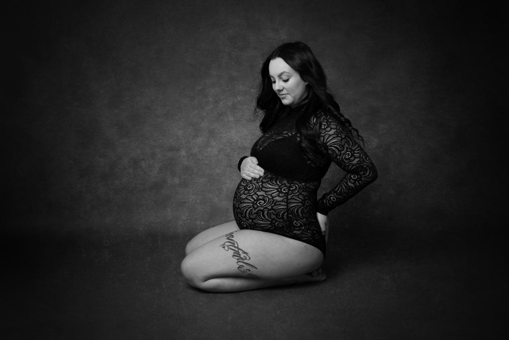 schwangere sitzt auf dem boden und traegt einen schwarzen body, schwangerschaftsfotos, carina rosen, fotograf lohmar