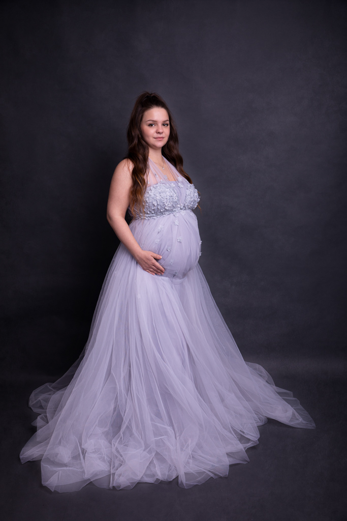 Schwangere im blauen Tüllkleid, ihre Hände lieben auf dem Babybauch. Schwanergschaftsfotos von Carina Rosen, Lohmar bei köln